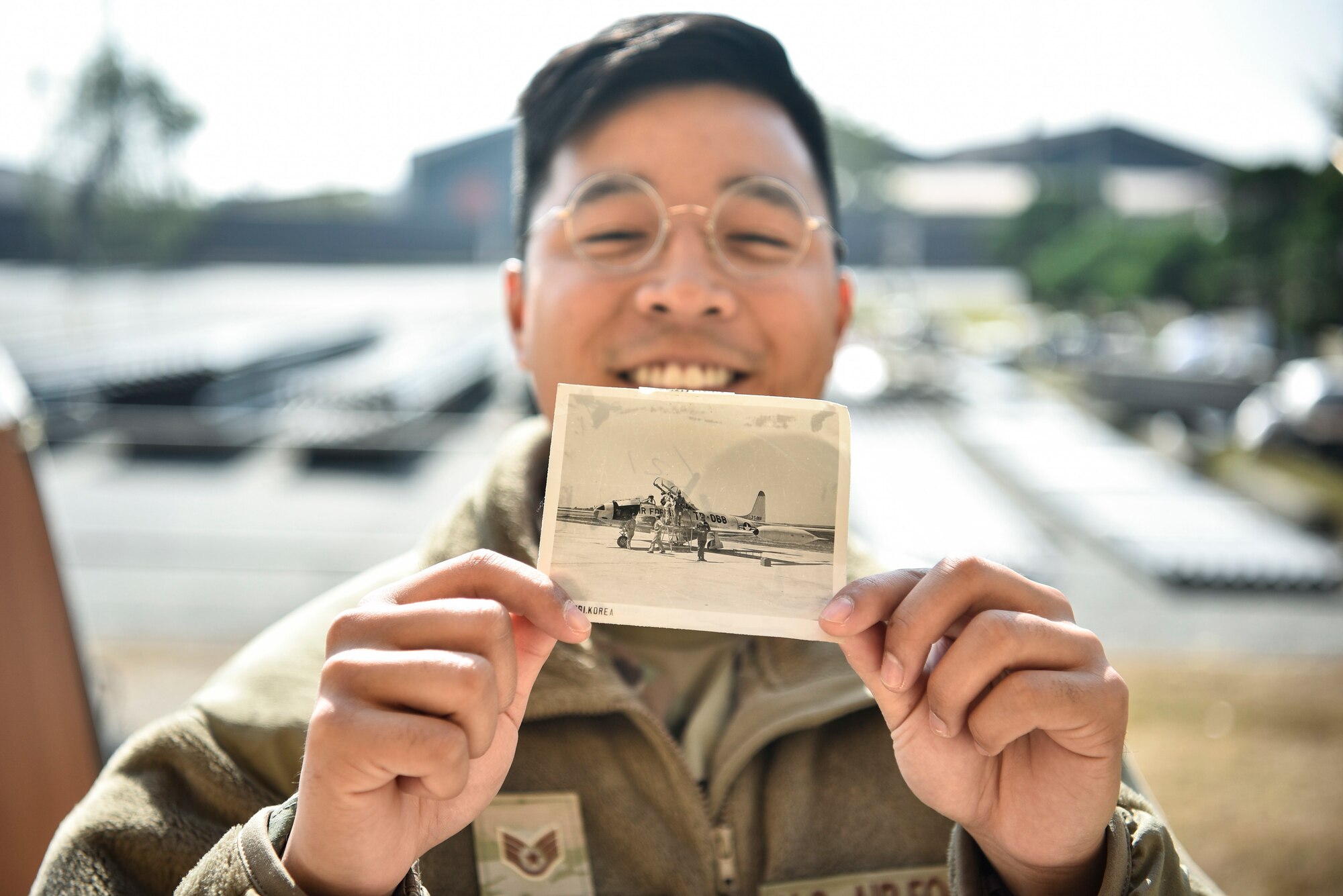 A photo of an Airman holding an old photo from the 1960s.