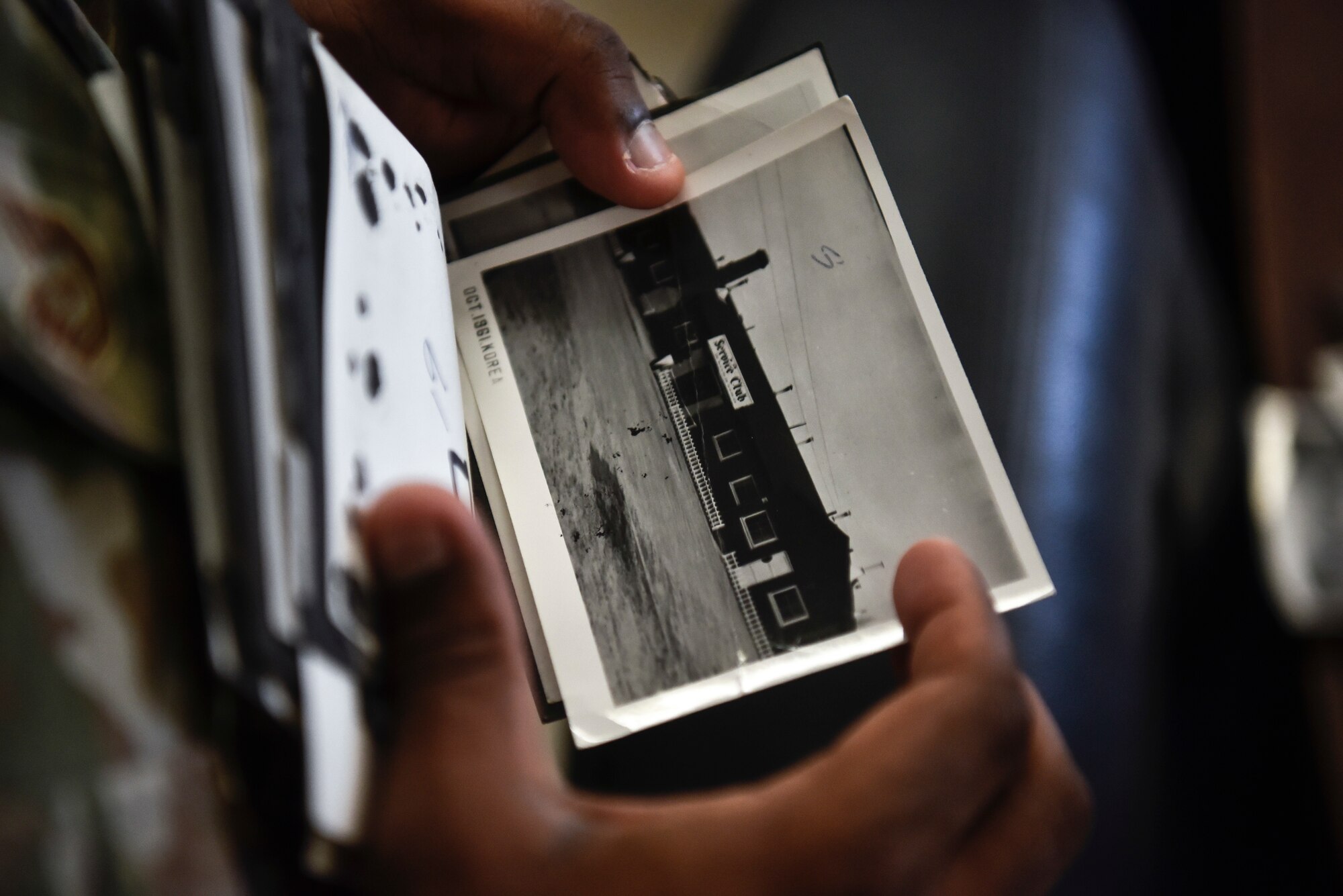 A photo of an Airman holding an old photo from the 1960s.