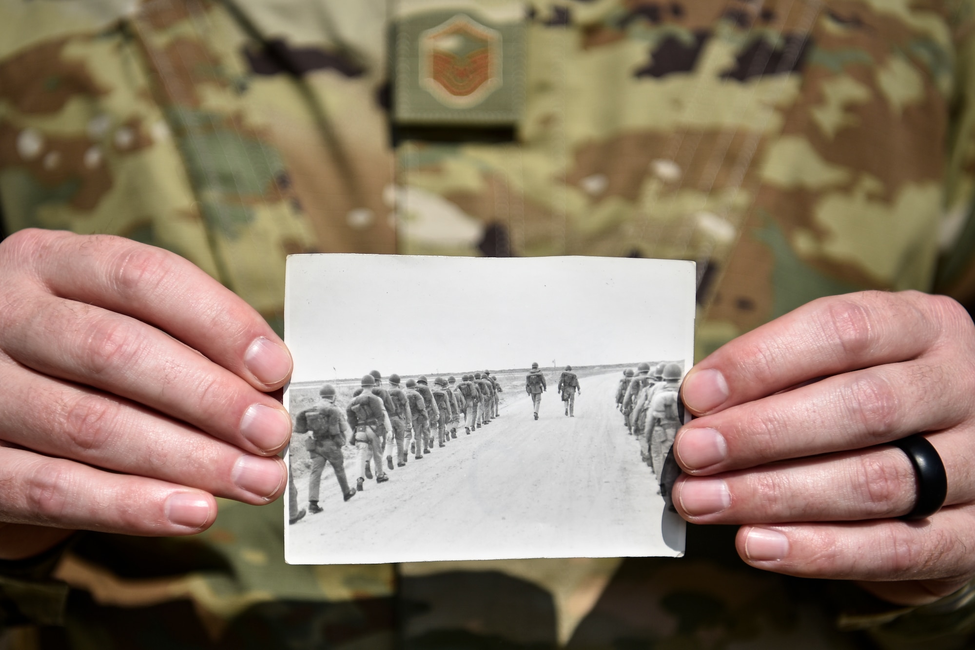 A photo of an Airman holding an old photo from the 1960s.