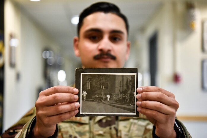 A photo of an Airman holding an old photo from the 1960s.
