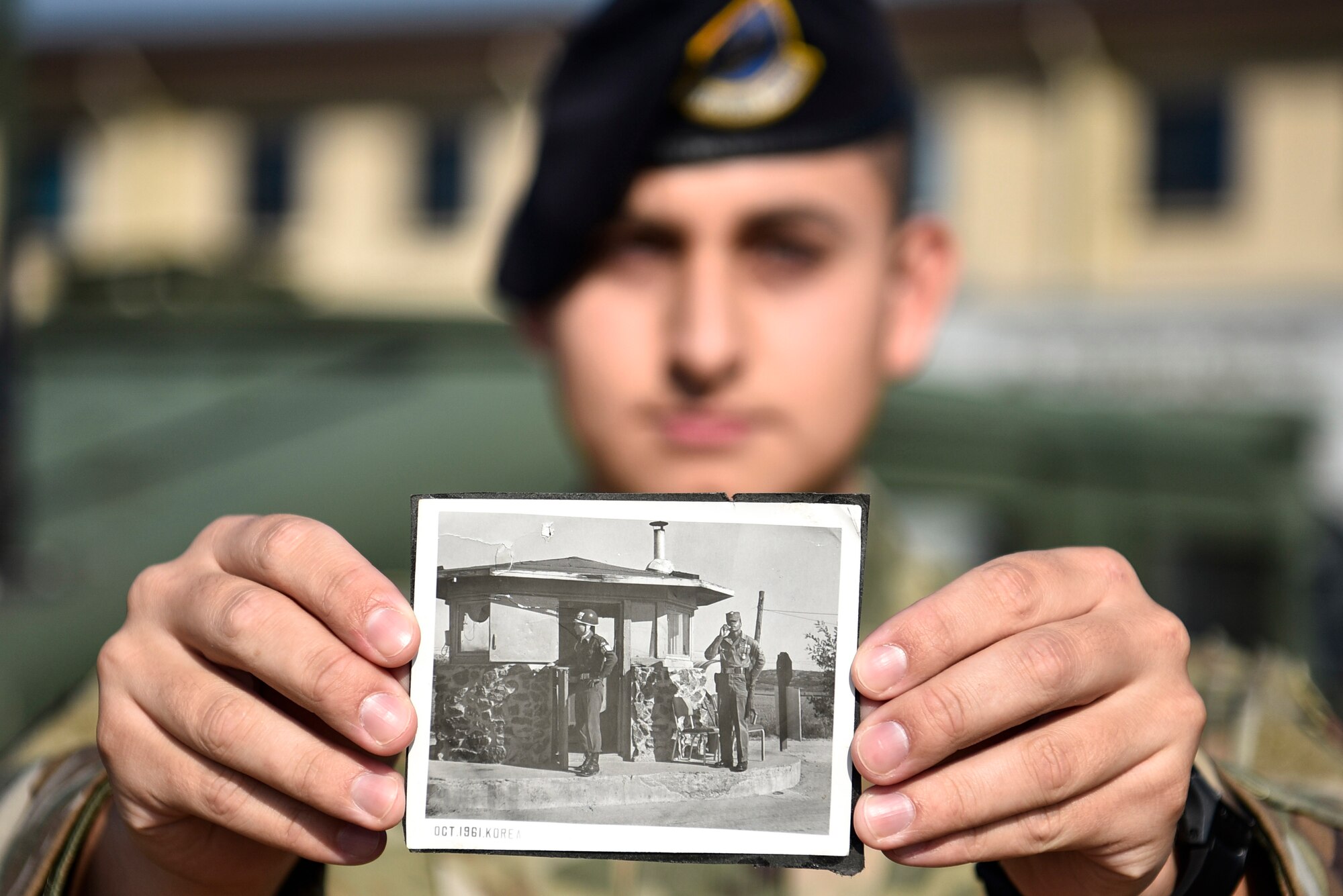 A photo of an Airmen holding a photo from the 1960s.