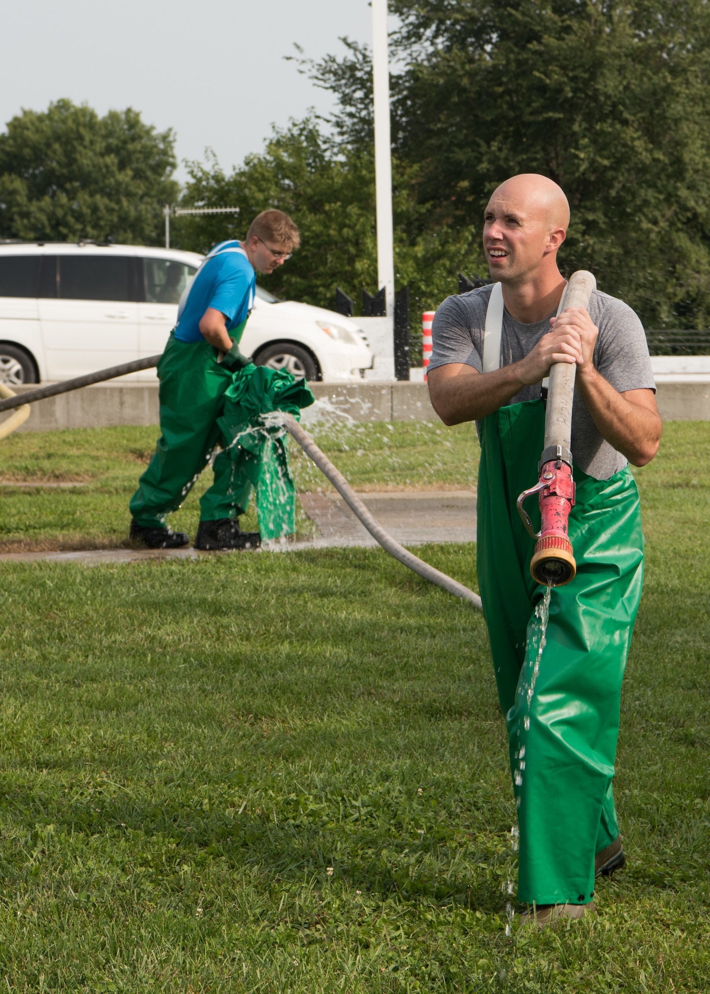 Two Airmen carry a fire hose.