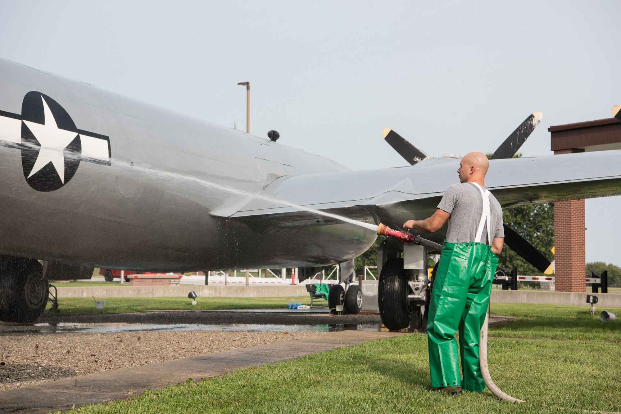 Technical Sergeant Clay Walton, 509th Aircraft Maintenance Squadron washes a B-29 Superfortress with a fire hose.