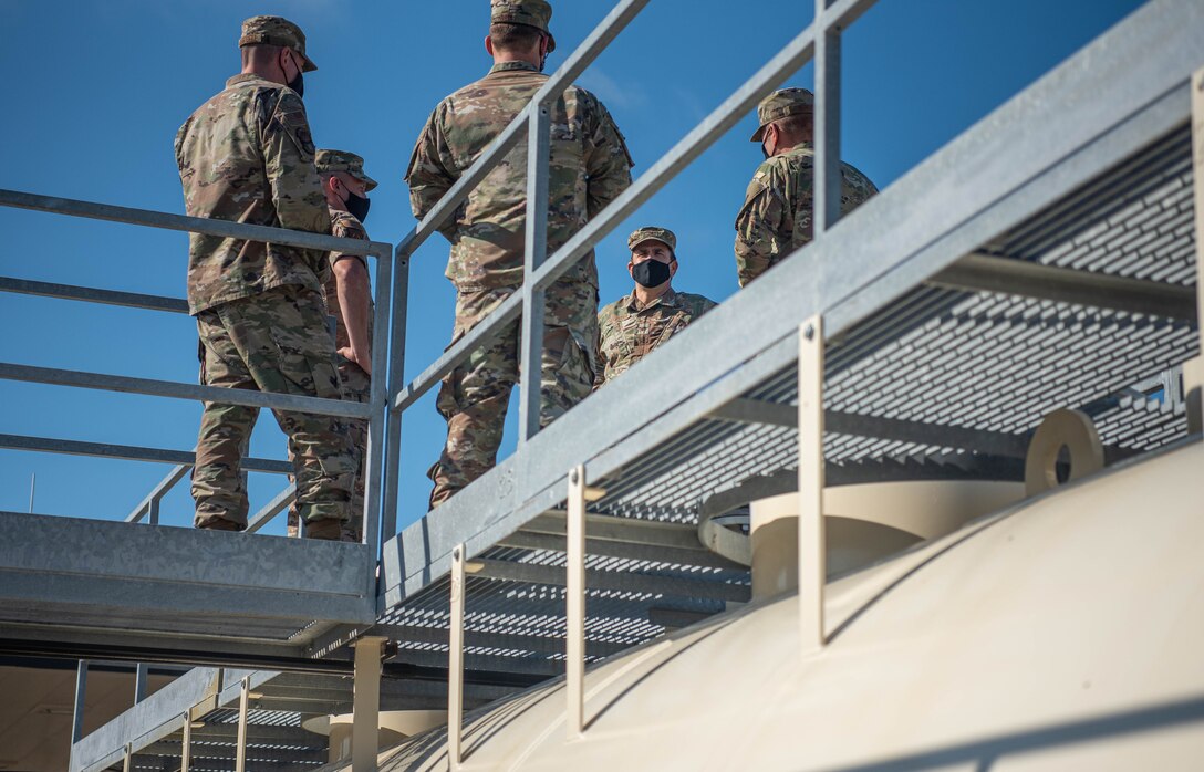 Airmen speak to each other above fuel tanks.