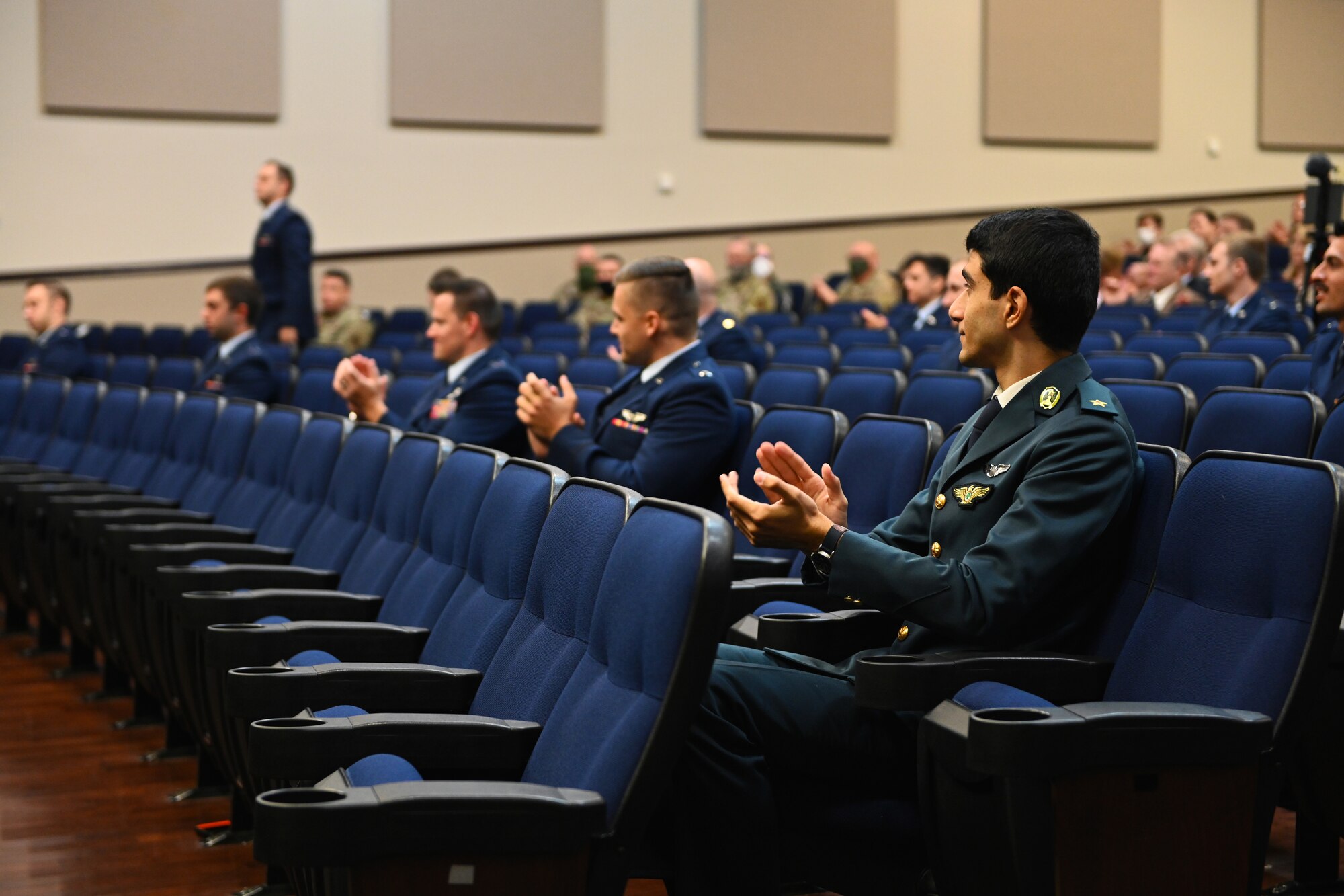 U.S. Air Force and international student pilots from class 21-01 clap for one of their fellow classmates heading to the stage Oct. 23, 2020, on Columbus Air Force Base Miss. As a result of COVID-19 restrictions the graduation was live streamed to Facebook on the Columbus AFB page for viewers not in attendance. (U.S. Air Force photo by Senior Airman Jake Jacobsen)