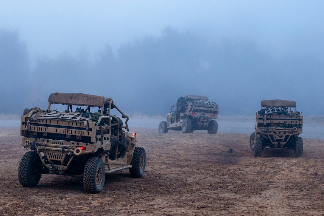 Three military vehicles drive near each other.