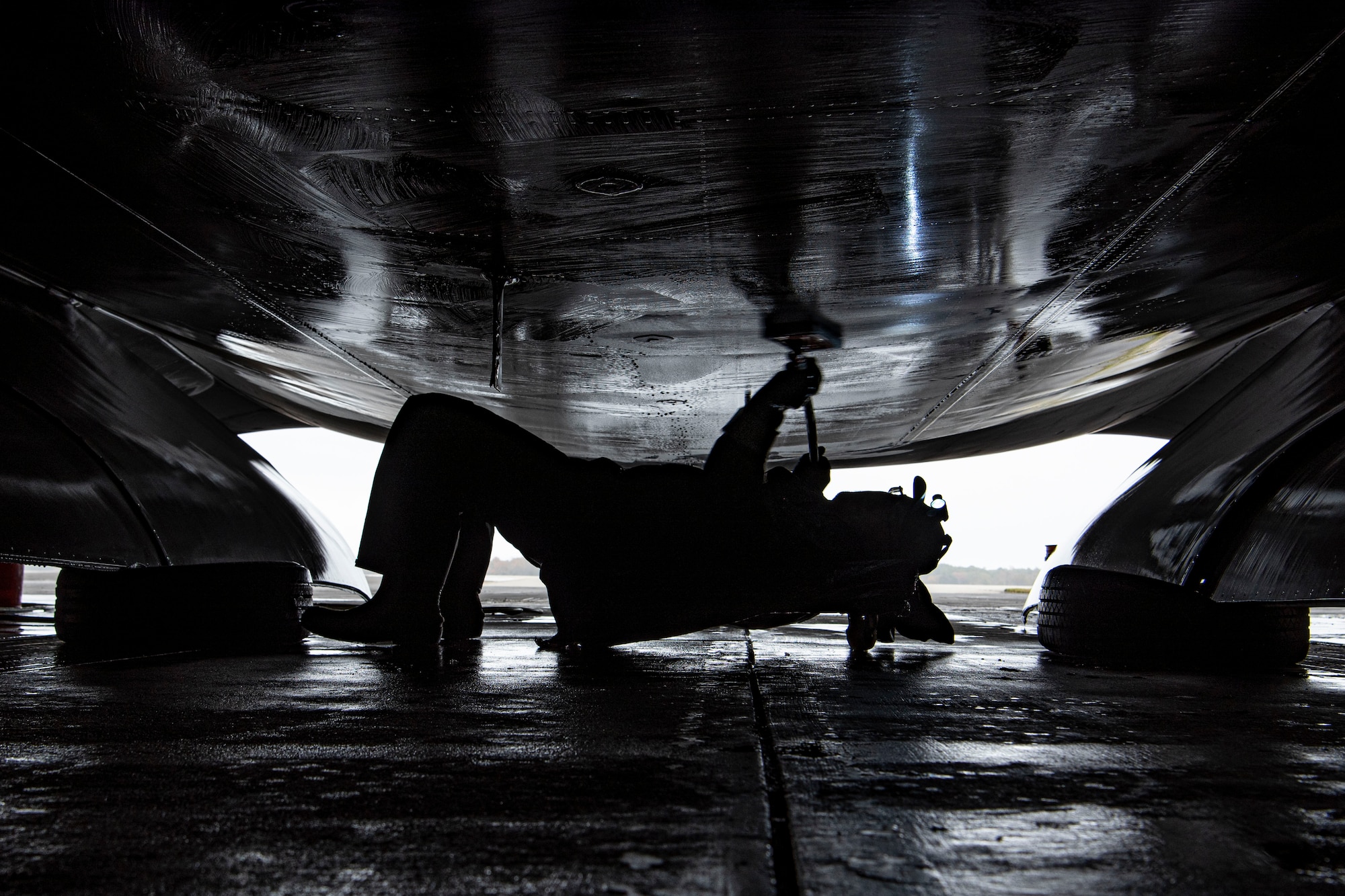 Photo of an aircraft wash specialist cleaning the underside of a C-17 Globemaster III.