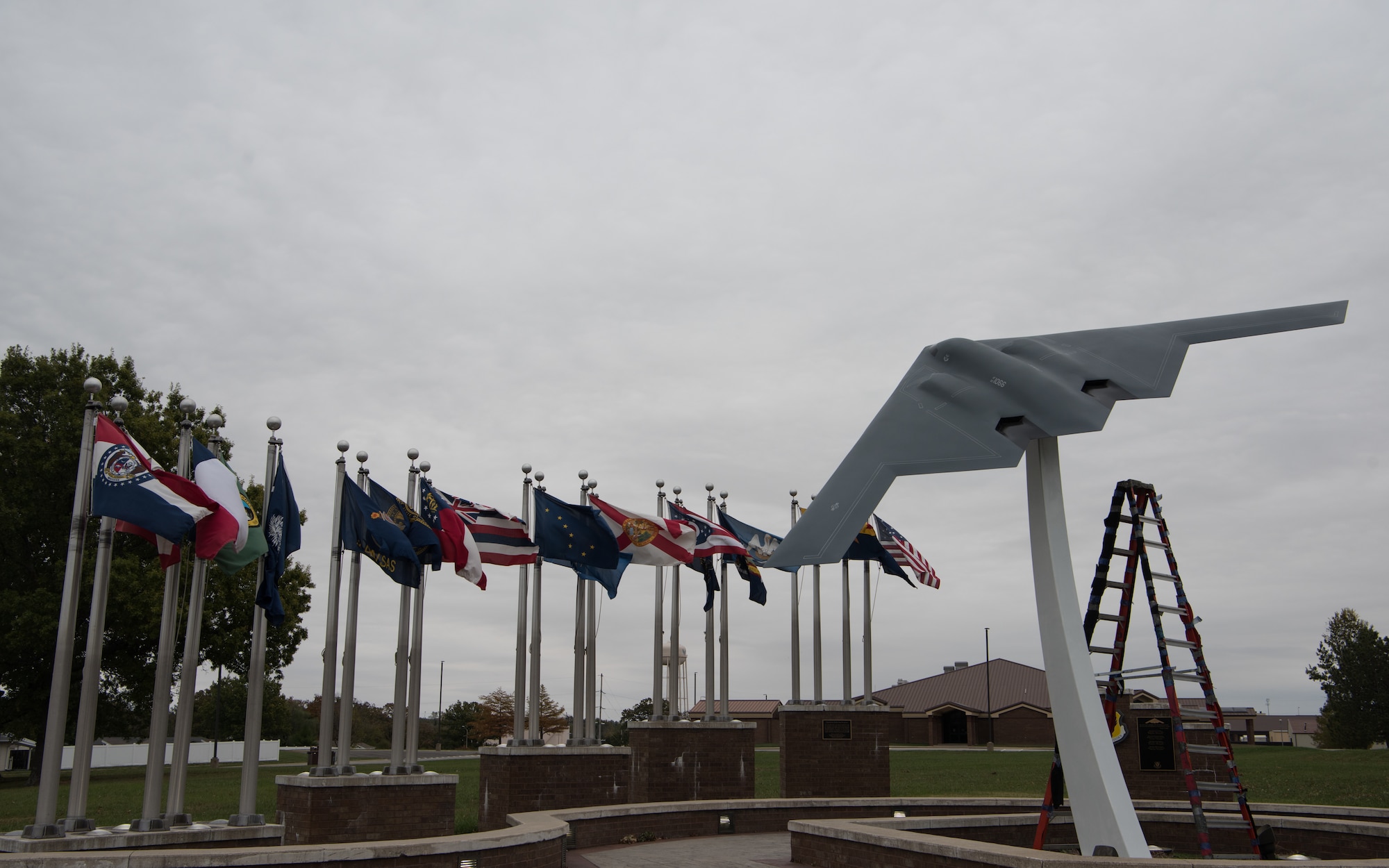 The B-2 Spirit static display sits on its pedestal in front of a set of state flags.