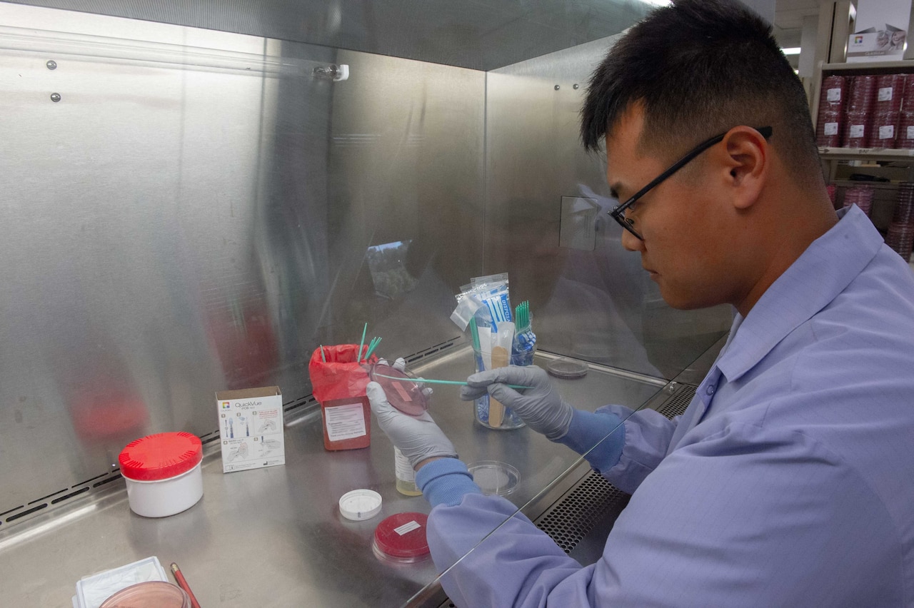 A sailor prepares a patient sample for lab testing.