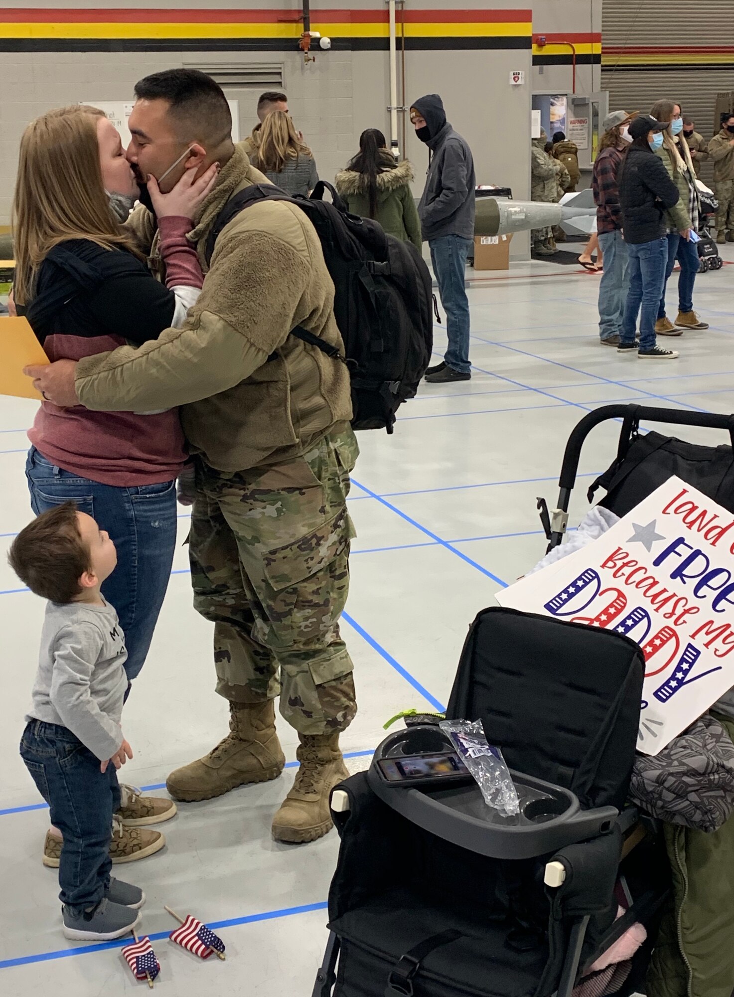 Staff Sgt. Jevon Rondeau and his wife, Sydney, share a kiss as their two-year-old son Dawson looks on. Jevon arrived home Sunday following a deployment to Al Dhafra Air Base, United Arab Emirates.