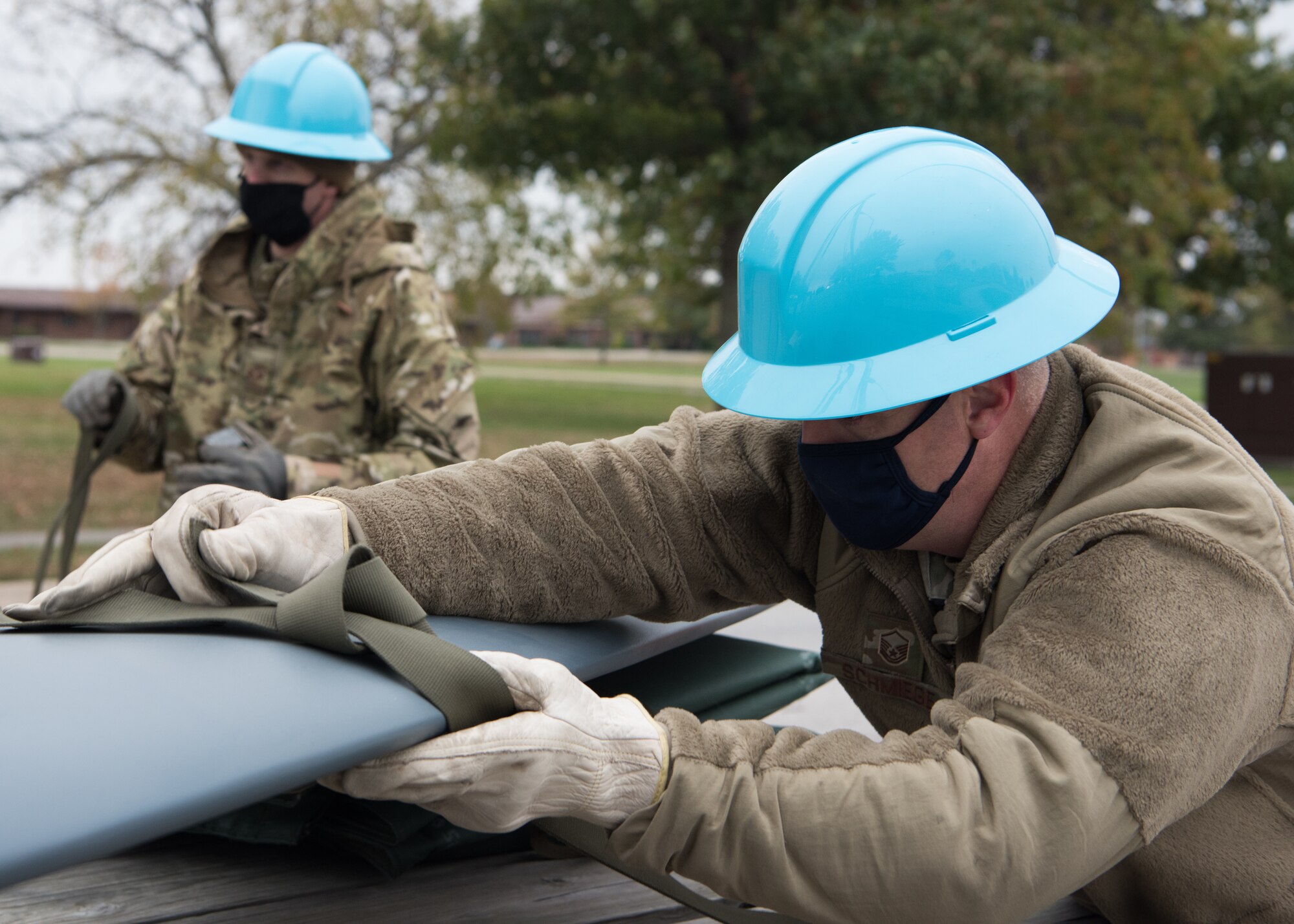 Two Airmen tie off straps on the wing of the B-2 static display.