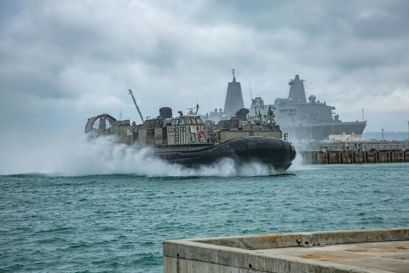 A hovercraft type amphibious vehicle plows through the water.