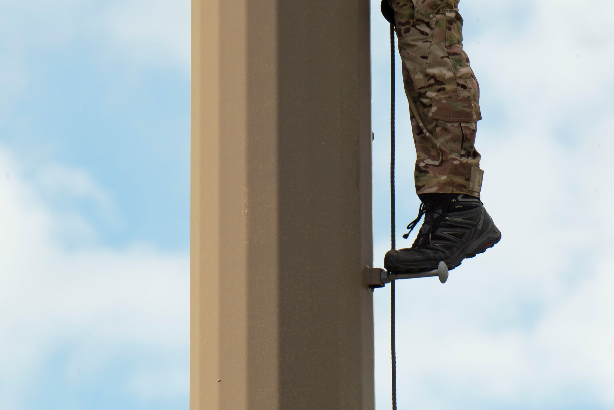 A photo of an Airman standing on a pole step during an antenna inspection.