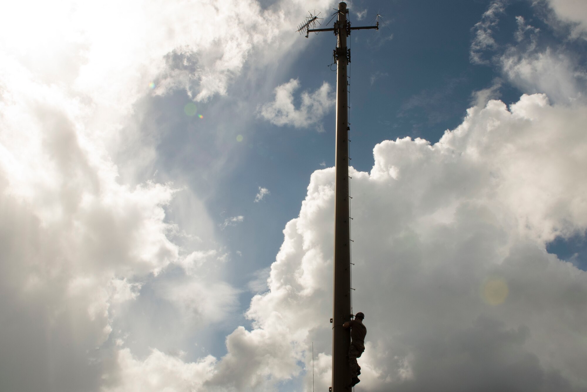 A photo of an Airman climbing down a communications tower.