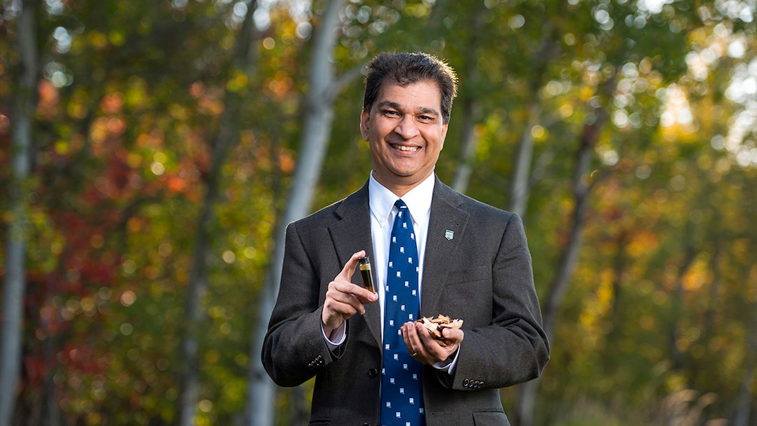 Dr. Hemant Pendse holds a small sample of wood chips and resulting synthetic crude oil.