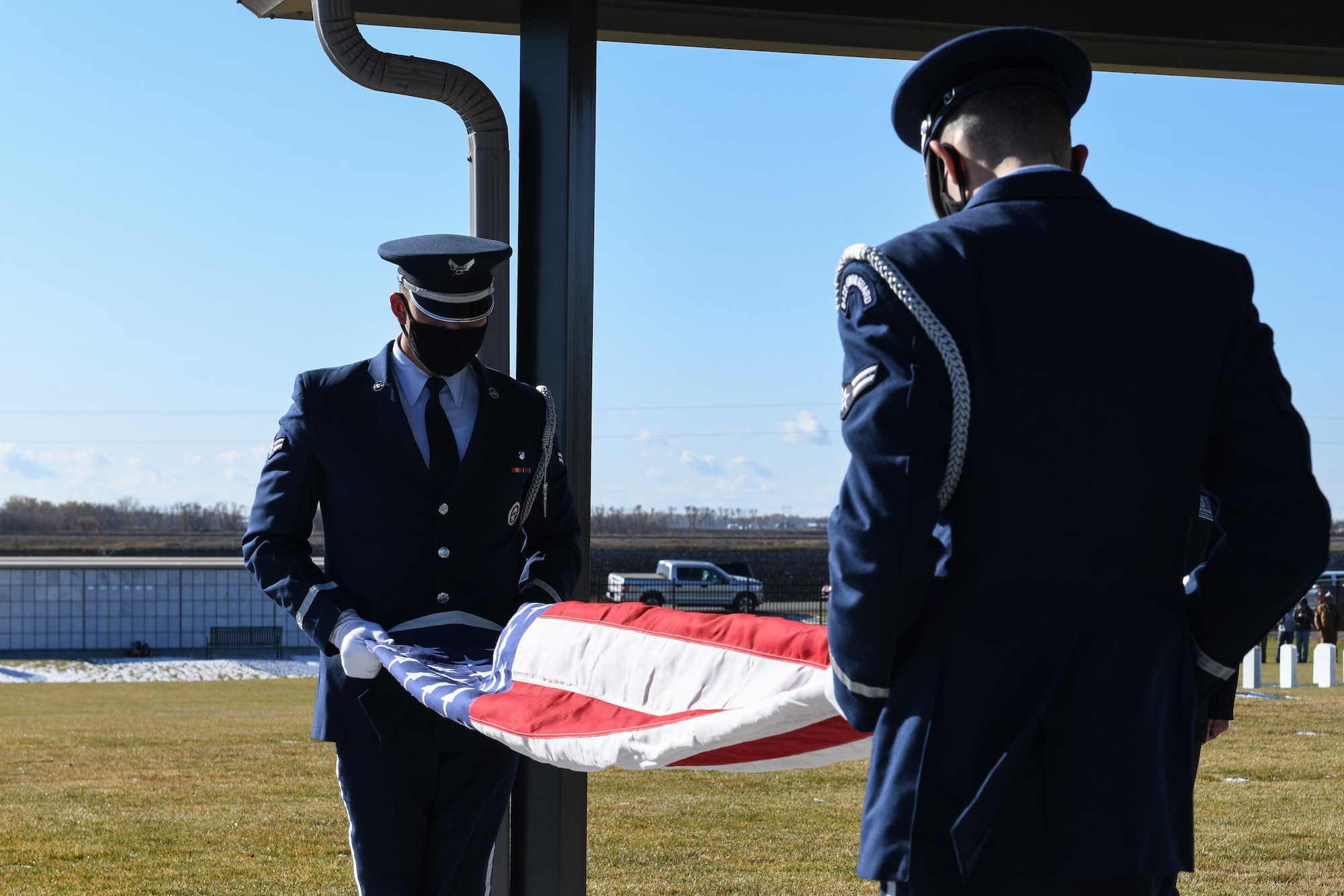 Two honor guardsmen from Grand Forks Air Force Base fold the flag during a funeral service for an unclaimed veteran Oct. 16, 2020 at the Fargo National Cemetary, N.D. Lelan Arthur Derr, Iowa native, and United Stated Air Force veteran who served in the Vietnam War era between 1971 and 1975, died December 10, 2019. (U.S. Aire Force photo by Airman Ashley Richards)