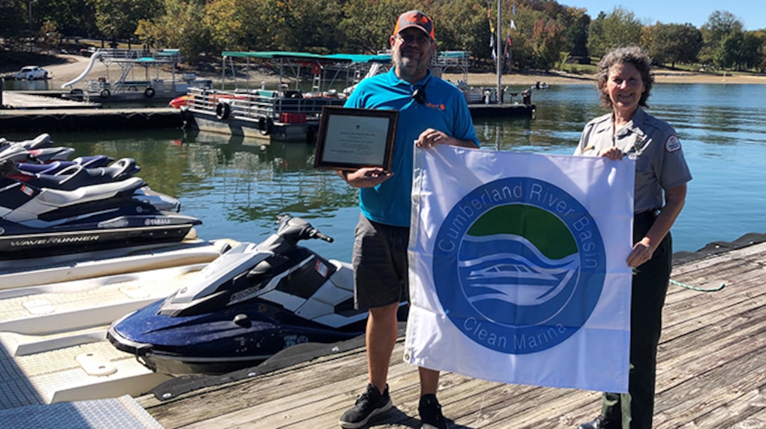 Park Ranger Sondra Carmen presents a plaque and “Clean Marina” flag to Sunset Marina Assistant Manager Brad Richardson at Dale Hollow Lake in Monroe, Tennessee, Oct. 13, 2020. (USACE Photo by Daniel Clark)