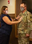 Newly promoted Lt. Col. Andrew Adamczyk’s wife, Rachael, places his new rank on during a promotion ceremony August 14 at Camp Lincoln in Springfield, Illinois.