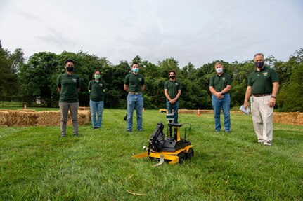 Engineers Stephanie Blease, Mei Ling McAfee and Isaac Downey stand with their Team Mentor Benjamin Gordon, Marine Corps Vulnerability and Protection Manager Rodney Peterson and Technical Director Larry Tarasek before competing in the TD Cup.