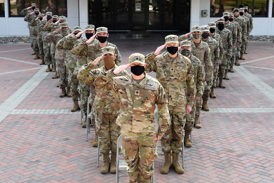 Service members wearing face masks stand in formation.