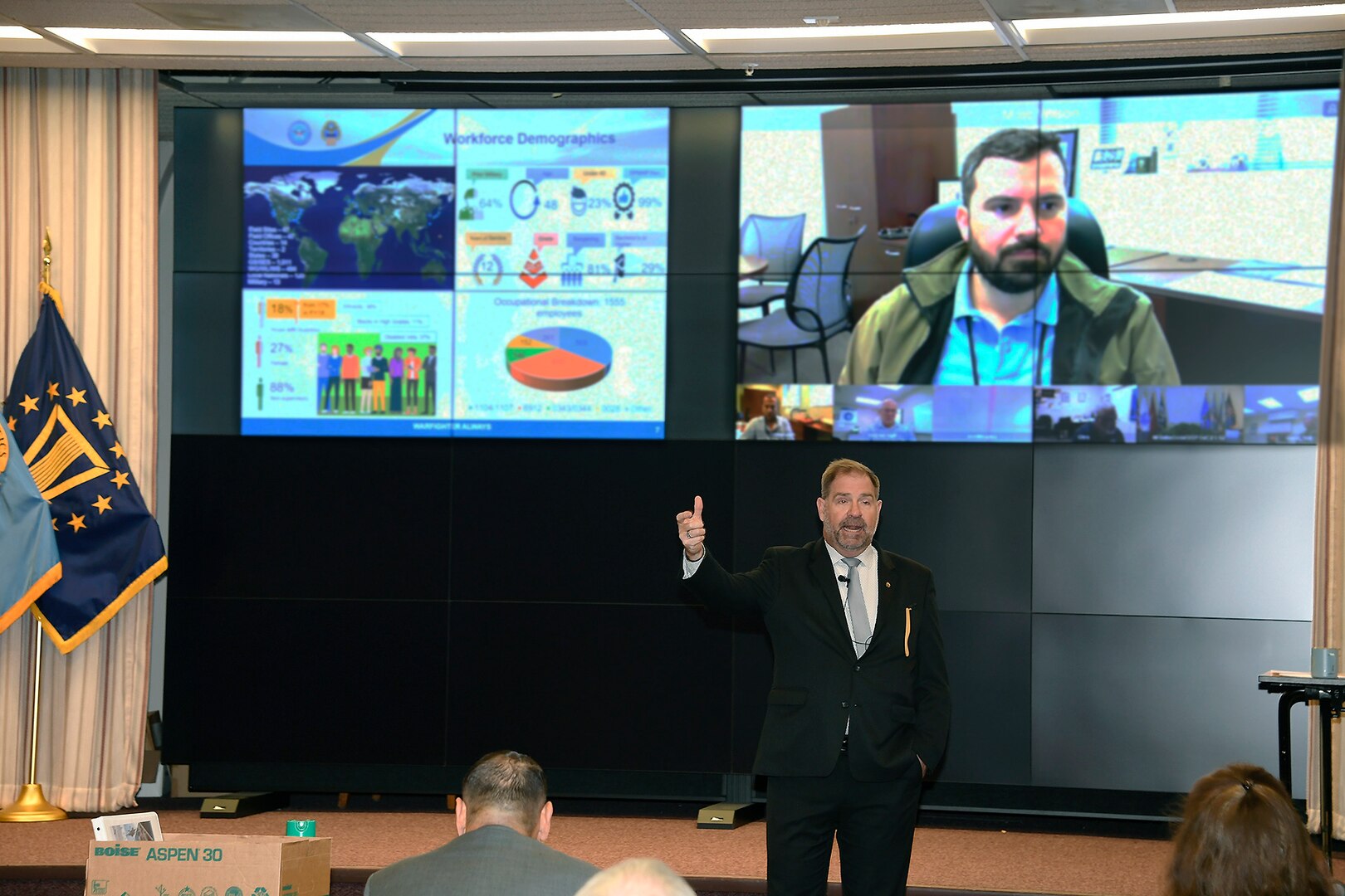 Command director speaks in front of large screens.