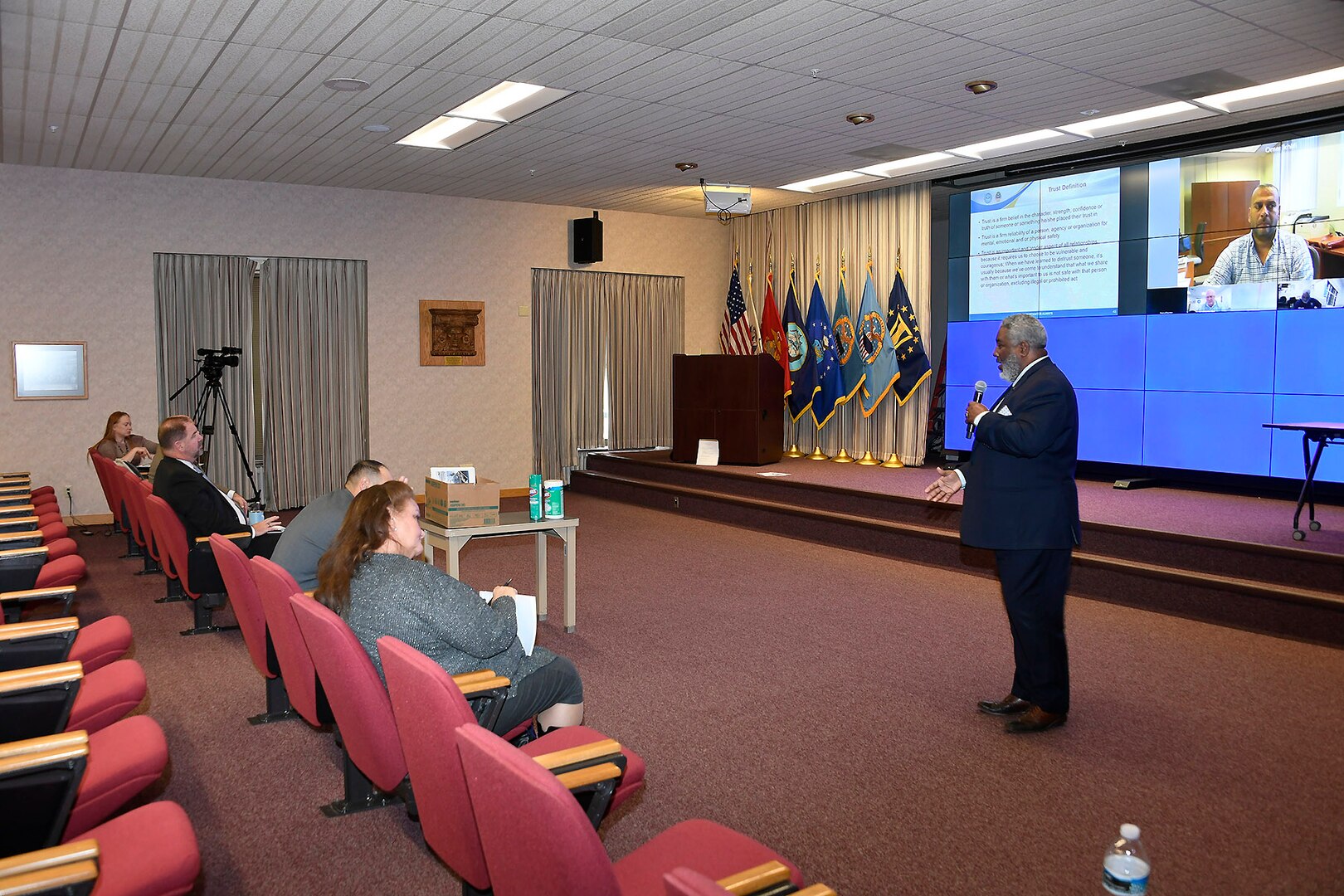 A man talks in front of a screen.