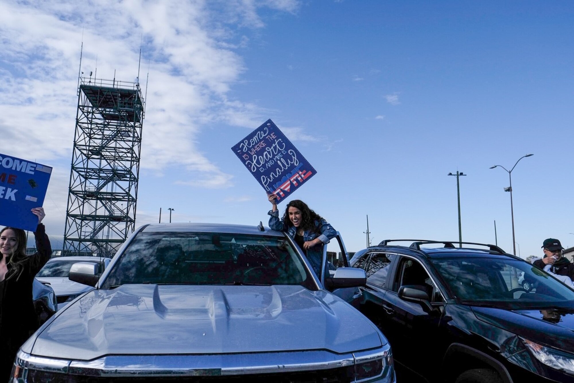 Family members hold up signs to welcome home Airmen assigned to the 729th Air Control Squadron.