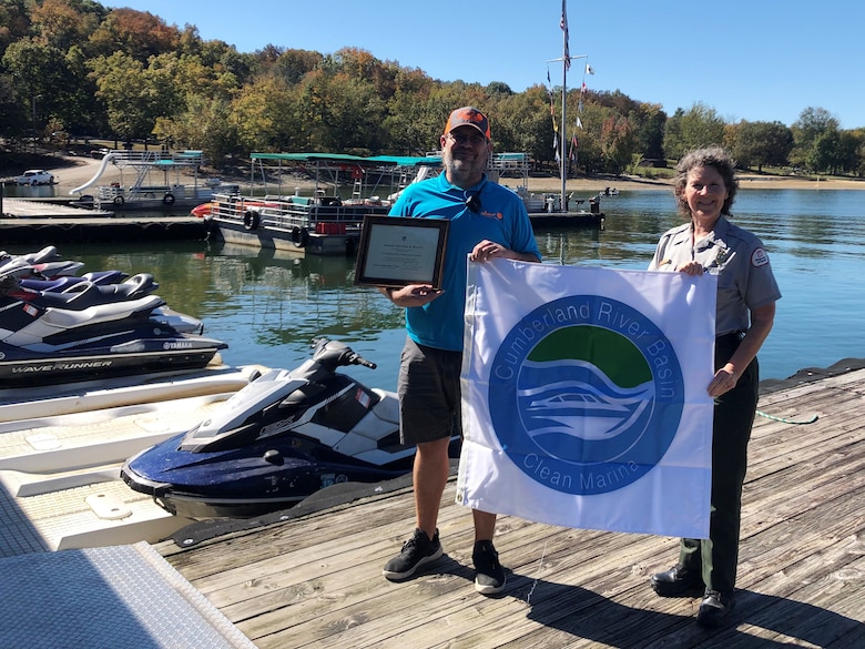 Park Ranger Sondra Carmen presents a plaque and “Clean Marina” flag to Sunset Marina Assistant Manager Brad Richardson at Dale Hollow Lake in Monroe, Tennessee, Oct. 13, 2020. (USACE Photo by Daniel Clark)