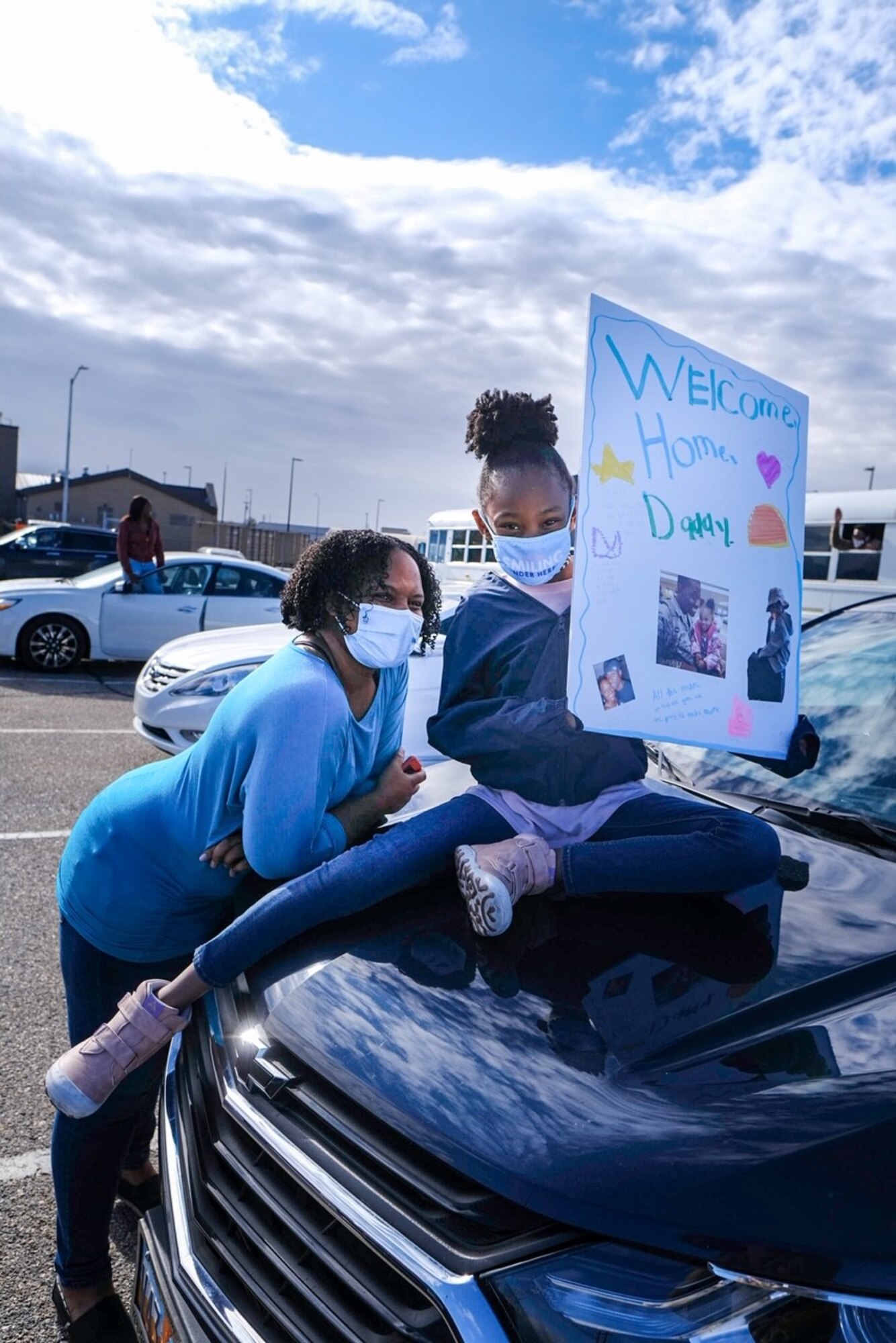 Family members hold up signs to welcome home Airmen assigned to the 729th Air Control Squadron.