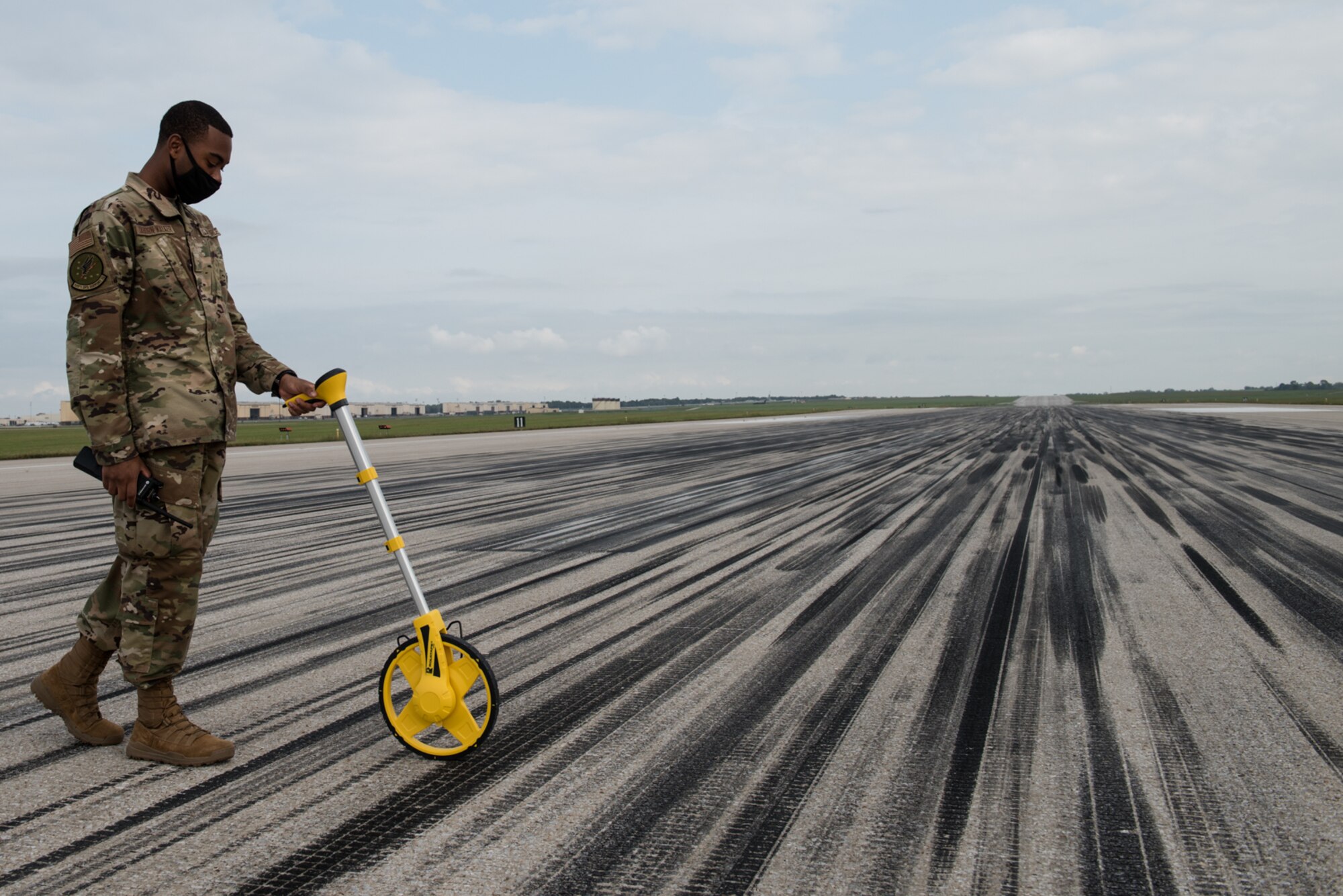 U.S. Air Force Airman Stephen Taborn-Walker, 509th Operation Support Squadron Airfield Management operations coordinator, practices measuring the width of the runway at Whiteman Air Force Base, Missouri, Sept. 23, 2020. The width of the runway determines what kind of aircraft can divert to Whiteman AFB, in case of an emergency. (U.S. Air Force photo by Airman 1st Class Christina Carter)