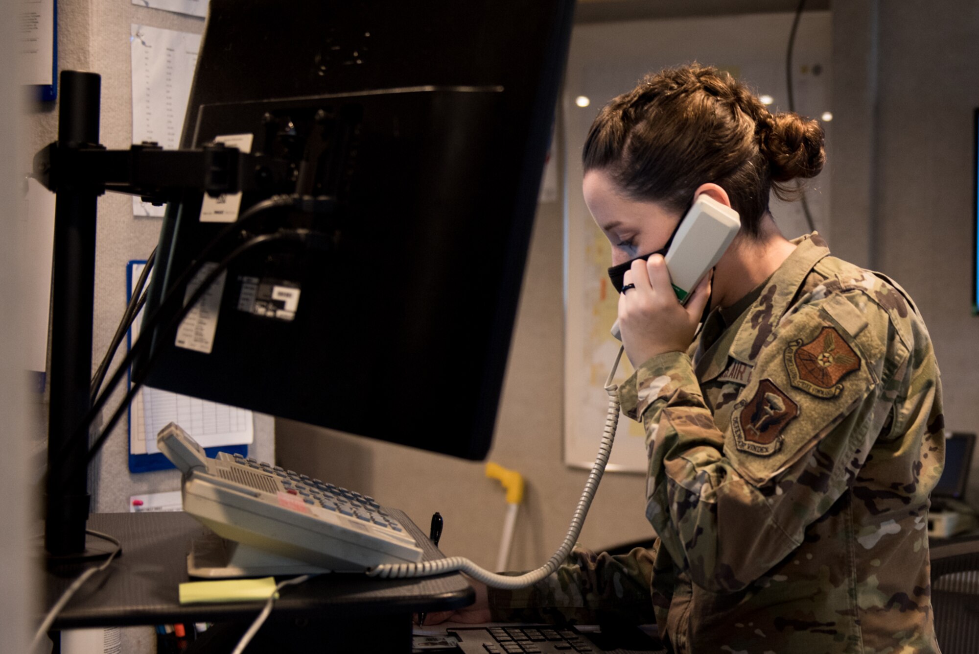 U.S. Air Force Airman 1st Class Enya Johnson, 509th Operation Support Squadron Airfield Management operations coordinator, answers the phone while working at the base operations desk at Whiteman Air Force Base, Missouri, Sept. 23, 2020. Johnson performs daily tasks like answering the alert phone, sending out weather warnings, inputting flight plans and performing airfield inspections. (U.S. Air Force photo by Airman 1st Class Christina Carter)