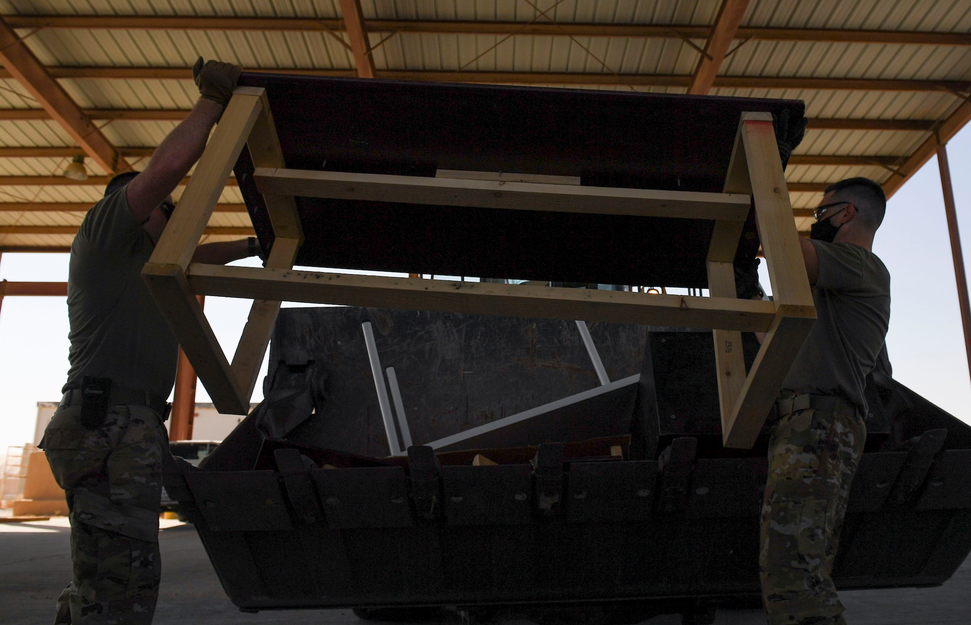 Demolition day volunteers place a table in a front end loader during a demolition day at Ali Al Salem Air Base, Kuwait, Oct. 21, 2020.