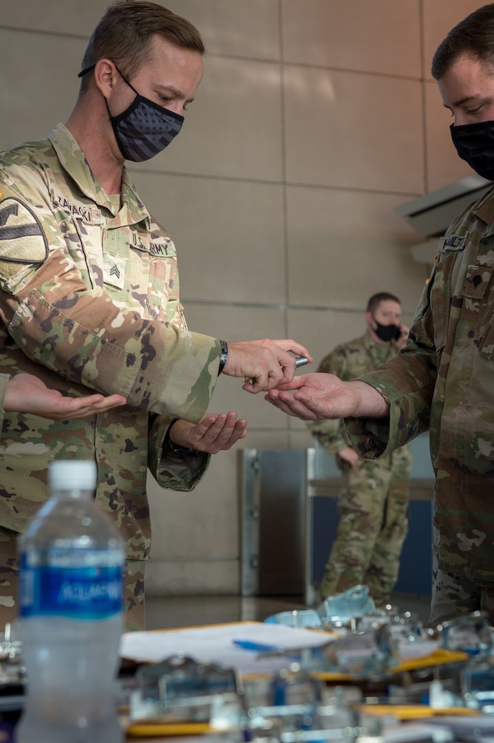 Army Sgt. Benjamin Zawacki and Spc. Kevin Hamilton, Soldiers assigned to 105th Military Police Company, Buffalo, N.Y., sanitize their hands between flight arrivals at Buffalo-Niagara International Airport Oct. 23, 2020. The team meets arriving passengers to distribute the State Department of Health traveler form to people coming from restricted states.