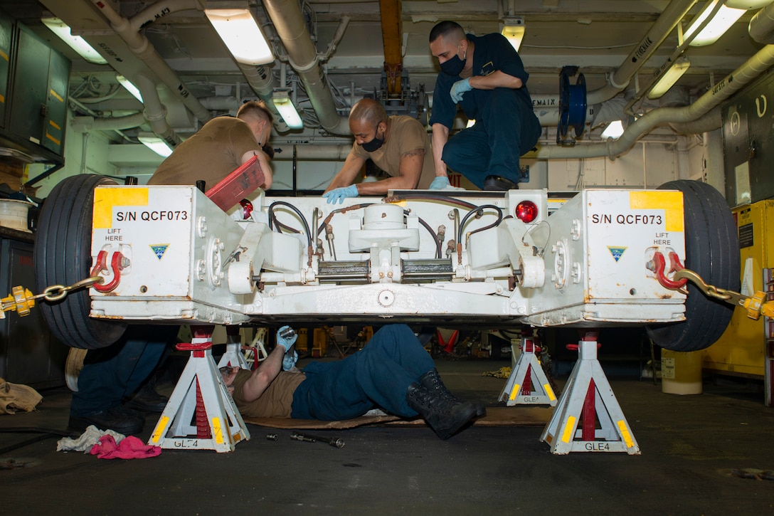 Sailors work on a large machine.