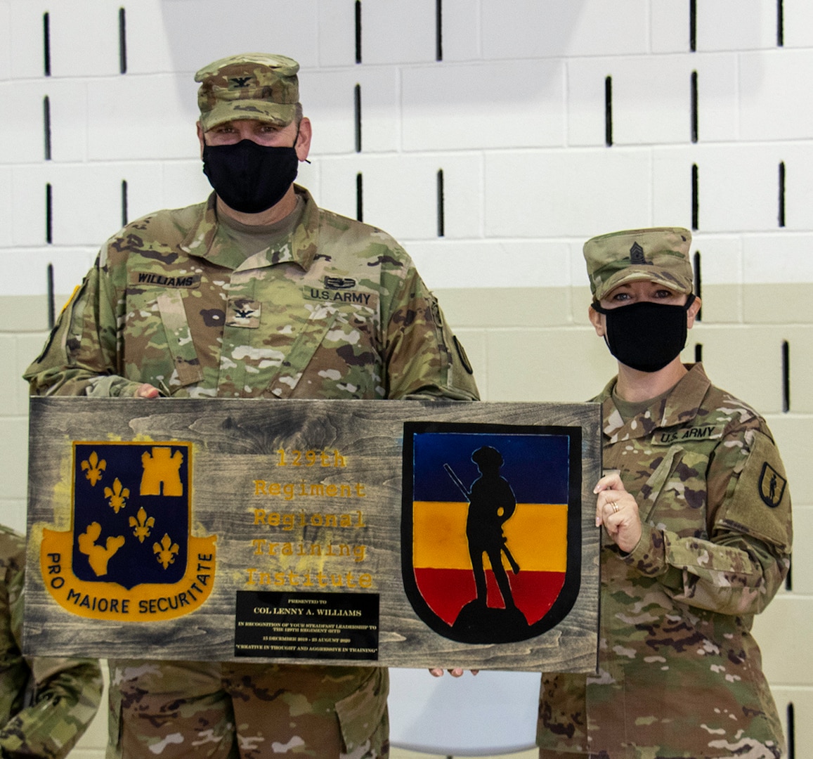 Command Sgt. Major Mary Dixon, of Chapin, Illinois, Commandant, 129th Regiment (RTI), based in Springfield, Illinois, presents Col. Lenny Williams, of Dyer, Indiana, with a gift from the Regiment during a change of command ceremony Aug. 23 at the Illinois Military Academy, Camp Lincoln, Springfield, Illinois.