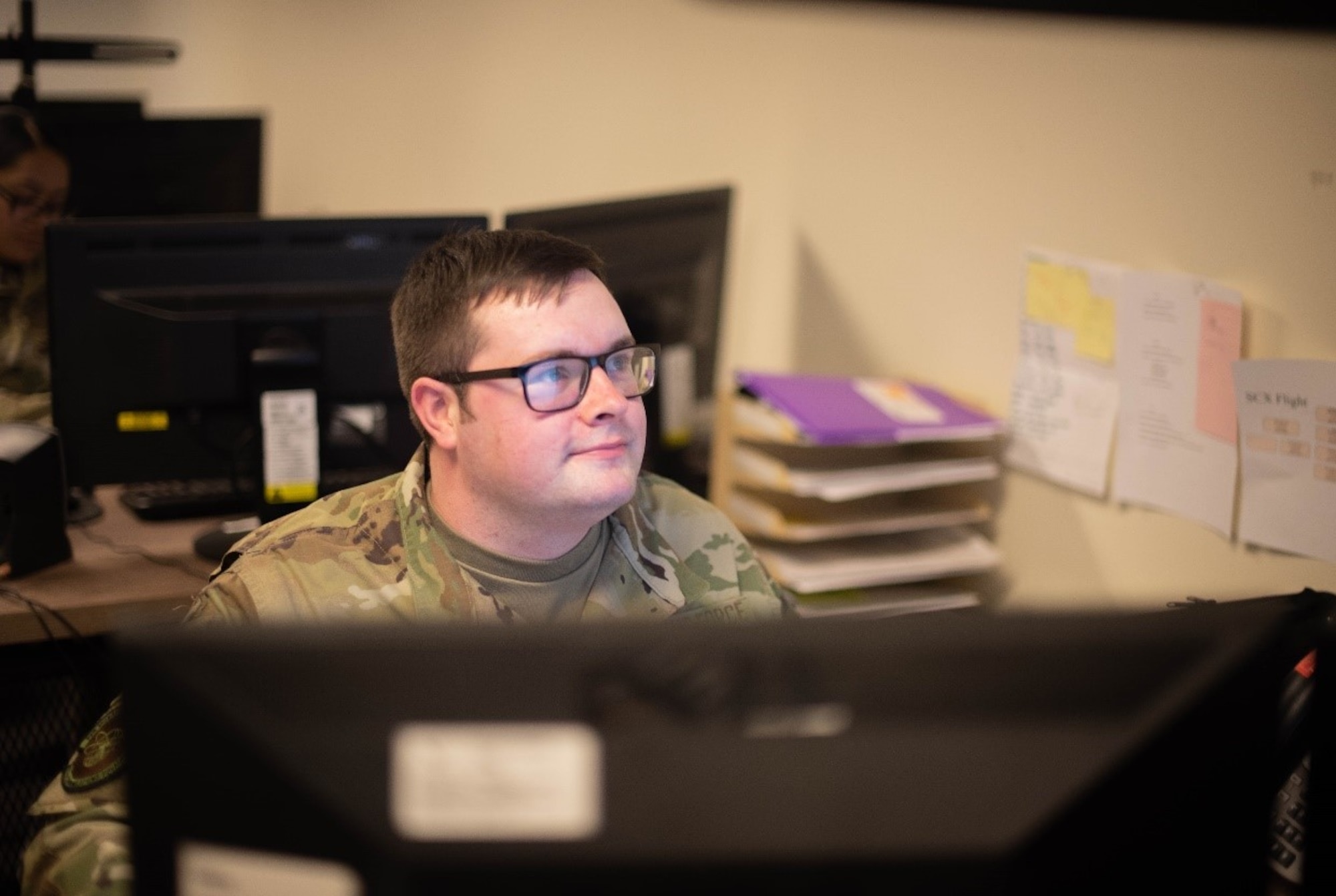 An Airman sits at his desk.