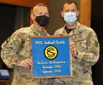 Maj. Kyle Scifert, of Elgin, Illinois, Commander, Illinois Army National Guard Officer Candidate School, presents Master Sgt. Joshuah Carlile, of Bourbonnais, Illinois, a gift from the Illinois Army National Guard Officer Candidate School