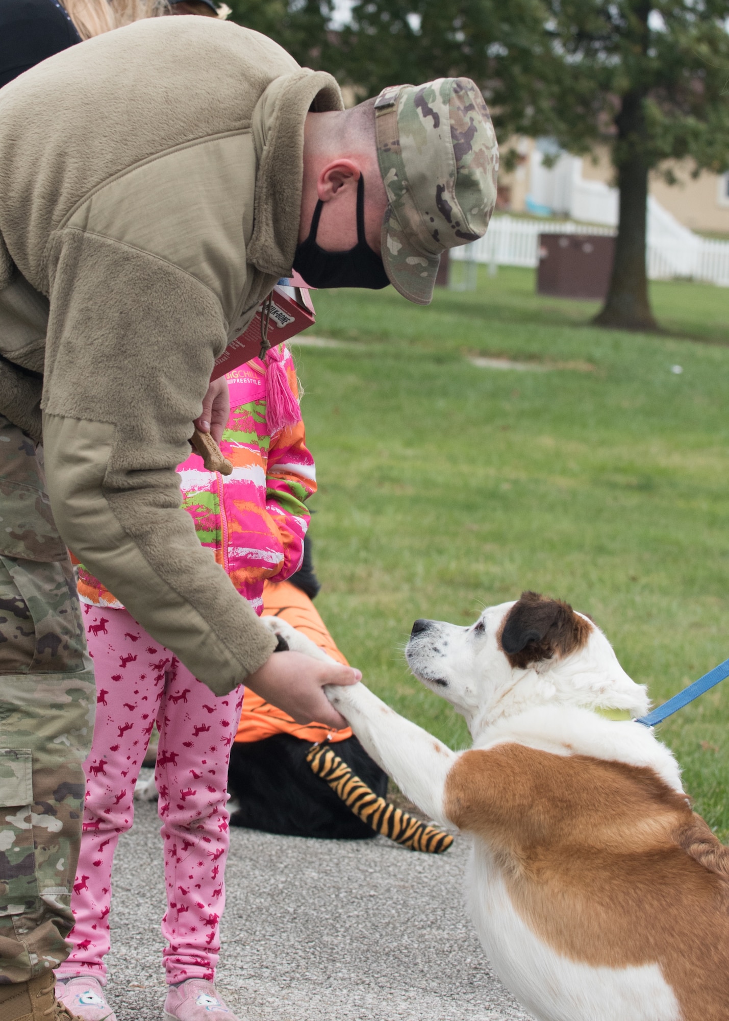Airman 1st Class Jonathan Russell, 509th Civil Engineer Squadron firefighter, shakes hands with Rocky, a Saint Bernard heeler dog before giving him a treat.