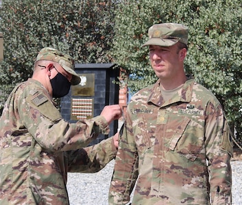 Lt. Col. Jason Osberg, of Champaign, Illinois, Commander, Bilateral Embedded Staff Team A25, presents Maj. Scott Liebhaber, of Chicago, with his combat patch which will be displayed on his right shoulder.
