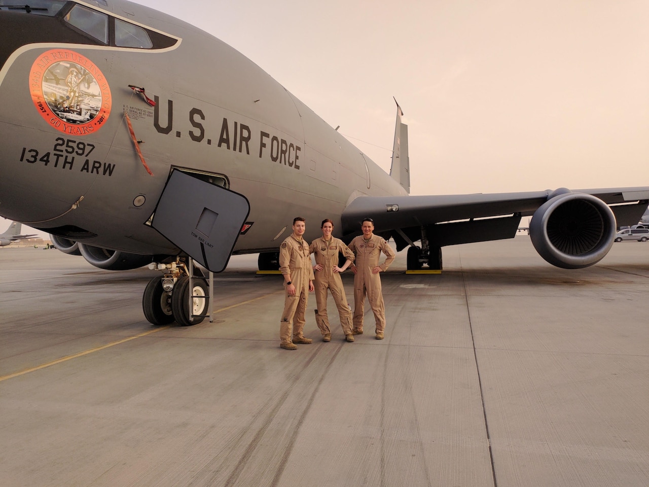Three people stand in front of a KC-135 Stratotanker aircraft.