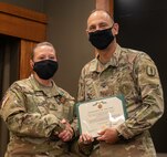 Newly promoted Sgt. 1st Class Lindsey Gibbs, of Pleasant Plains, Illinois, is presented with an Army Commendation Medal from Col. Daniel Reichen, of Springfield, Illinois, military personnel officer for the Illinois Army National Guard