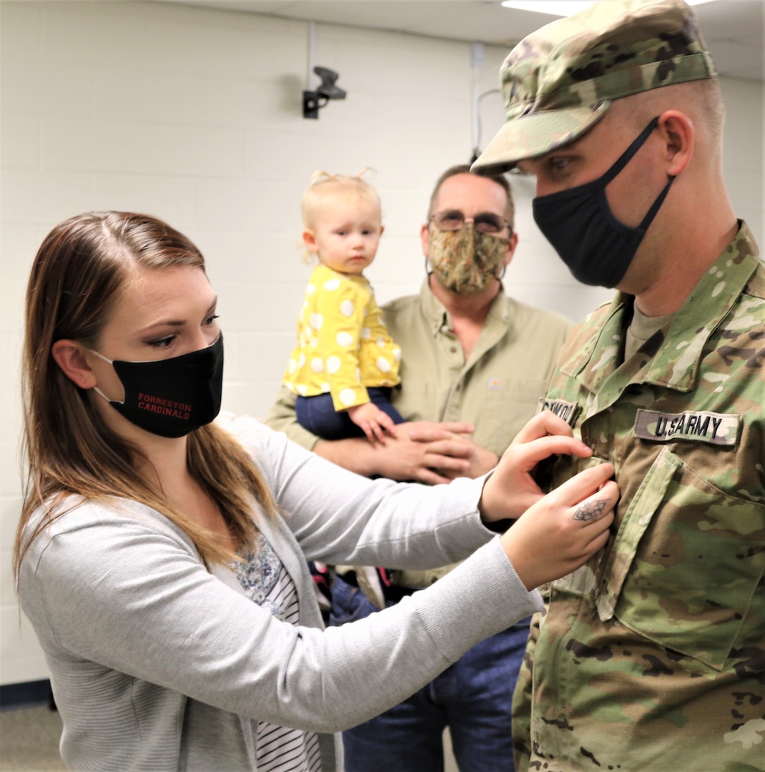 Audra Gronewold, wife of newly promoted Sgt. Timothy Gronewold, of Forreston, Illinois, places his new rank on his uniform during a promotion ceremony Oct. 18 at Camp Lincoln, Springfield, Illinois. Gronewold is assigned to the Illinois Army National Guard’s Headquarters and Headquarters Company, 129th Regiment (Regional Training Institute).