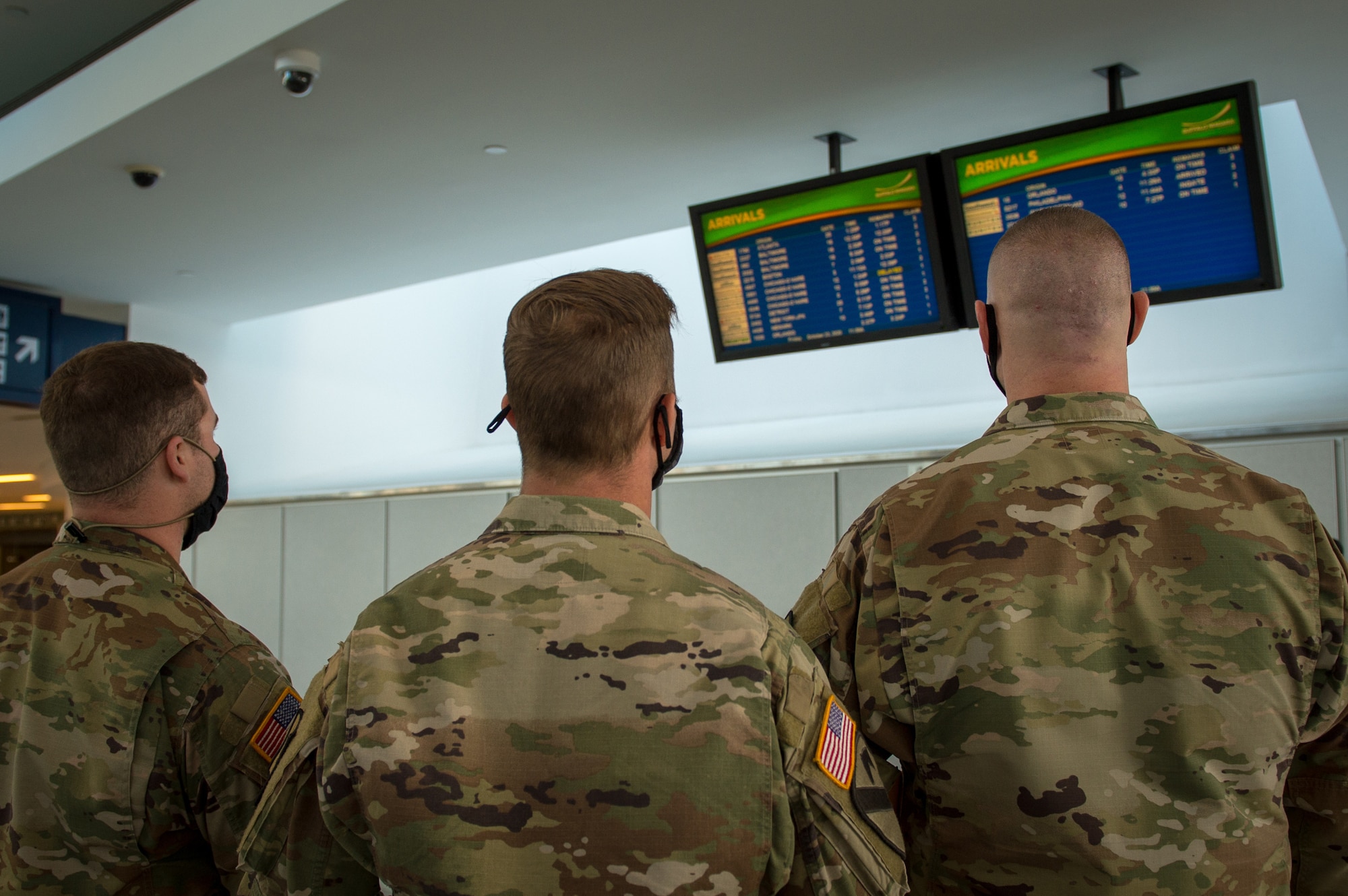 Army Spc. Kevin Hamilton, Sgt. Benjamin Zawacki and Staff Sgt. James Kociencki, Soldiers assigned to 105th Military Police Company, Buffalo, N.Y., check the arrival boards at Buffalo-Niagara International Airport, supporting the state’s travel advisory Oct. 23, 2020. The team meets arriving passengers to distribute the State Department of Health traveler form to travelers coming from restricted states.