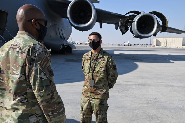 U.S. Air Force Staff Sgt. Anothy Pellegrini, assigned to the 8th Expeditionary Air Mobility Squadron, greets the 379th Air Expeditionary Wing Command Chief, Chief Master Sgt. Kenneth Bruce Oct. 23, 2020, at Al Udeid Air Base, Qatar. The Airmen of The Mighty Ocho are responsible for transporting an average of 10 million pounds of cargo and 5,000 passengers throughout the U.S. Central Command area of responsibility each month, accounting for more than 36 percent of airlift operations in Europe and Southwest Asia. (U.S. Air Force photo by Staff Sgt. Kayla White) (Photo altered to obscure identification badges for operational security)