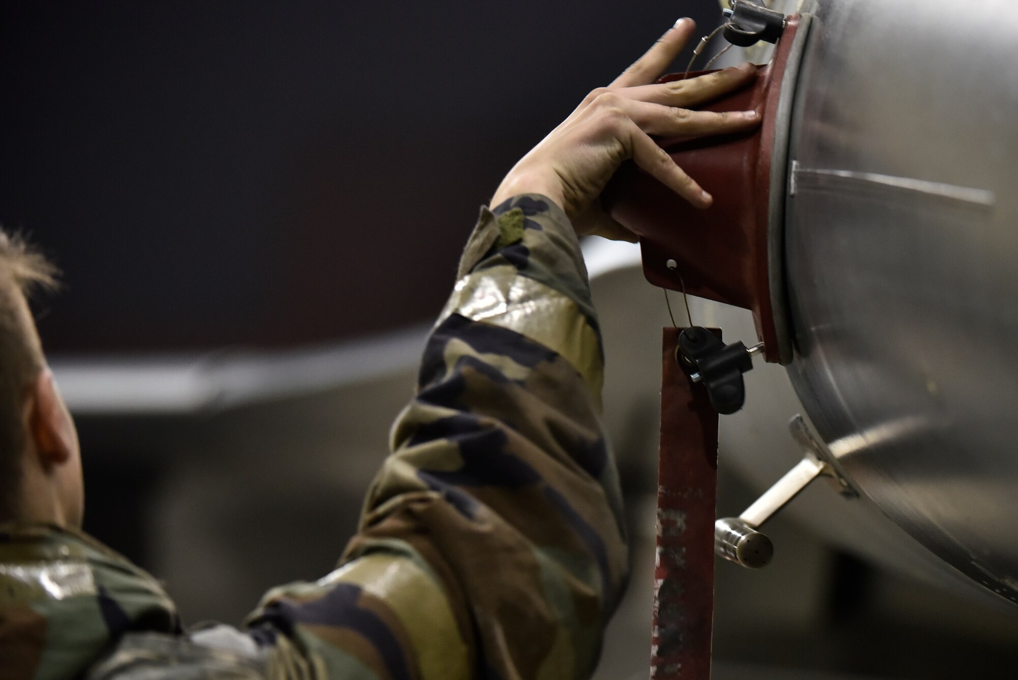 An Airmen removing a cover from an aircraft.