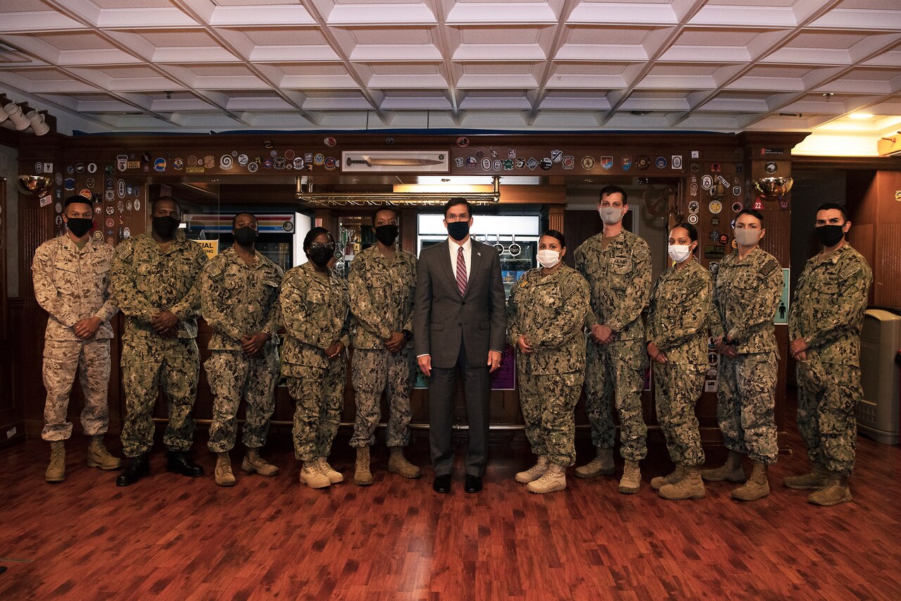 Defense Secretary Dr. Mark T. Esper stands with a group of service members.