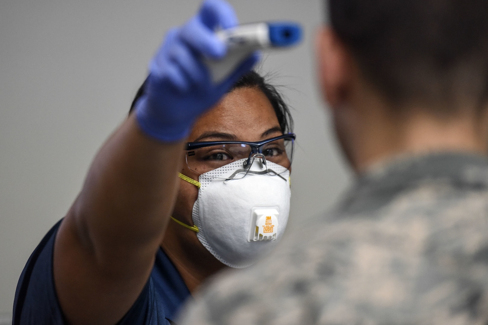 Kuhina Talimalie, 735th Air Mobility Squadron passenger service and baggage agent, uses a no-touch thermometer to check a service member's temperature at Joint Base Pearl Harbor-Hickam, Hawaii, March 25, 2020. Passenger terminal airmen are screening passengers for fever to help mitigate the spread of COVID-19.