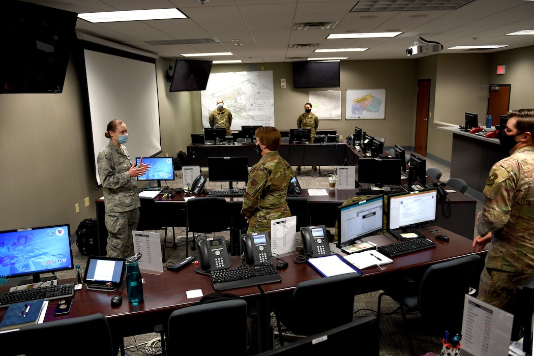Airmen stand in a room with computers.