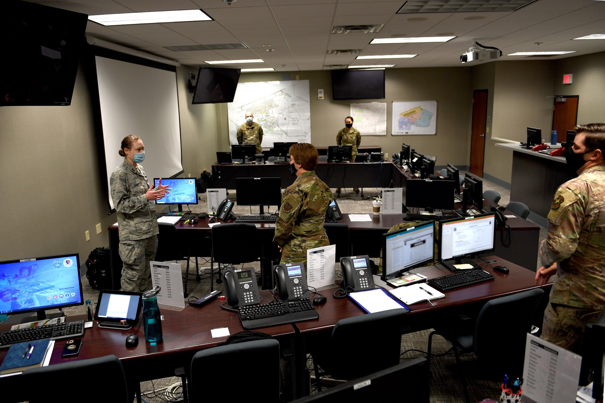 Airmen stand in a room with computers.