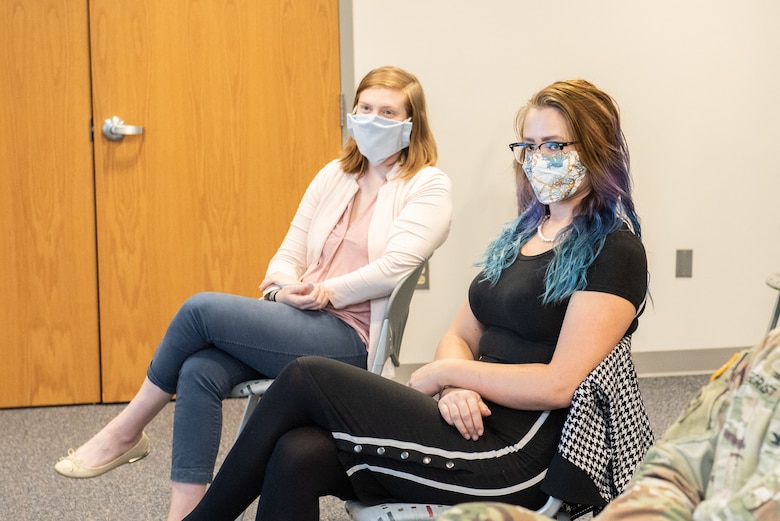 LDP Tier I participants engineer Katie Render and EEO specialist Anneliese Mielke listen to TAM Commander COL Philip Secrist and await their turns at the lectern as part of the socially distanced and virtual LDP Tier I graduation ceremony.